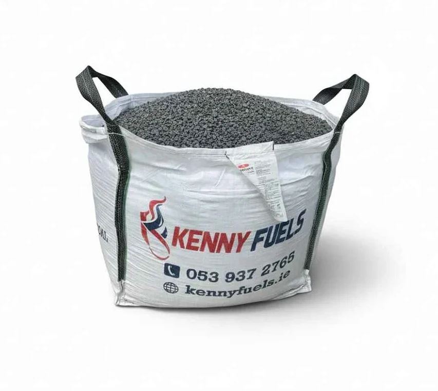 Large white bulk bag filled with dark granular fuel material, branded “KENNY FUELS” with a red and blue flame logo. The bag features black corner lifting straps and printed contact details, with an additional label attached to the front.