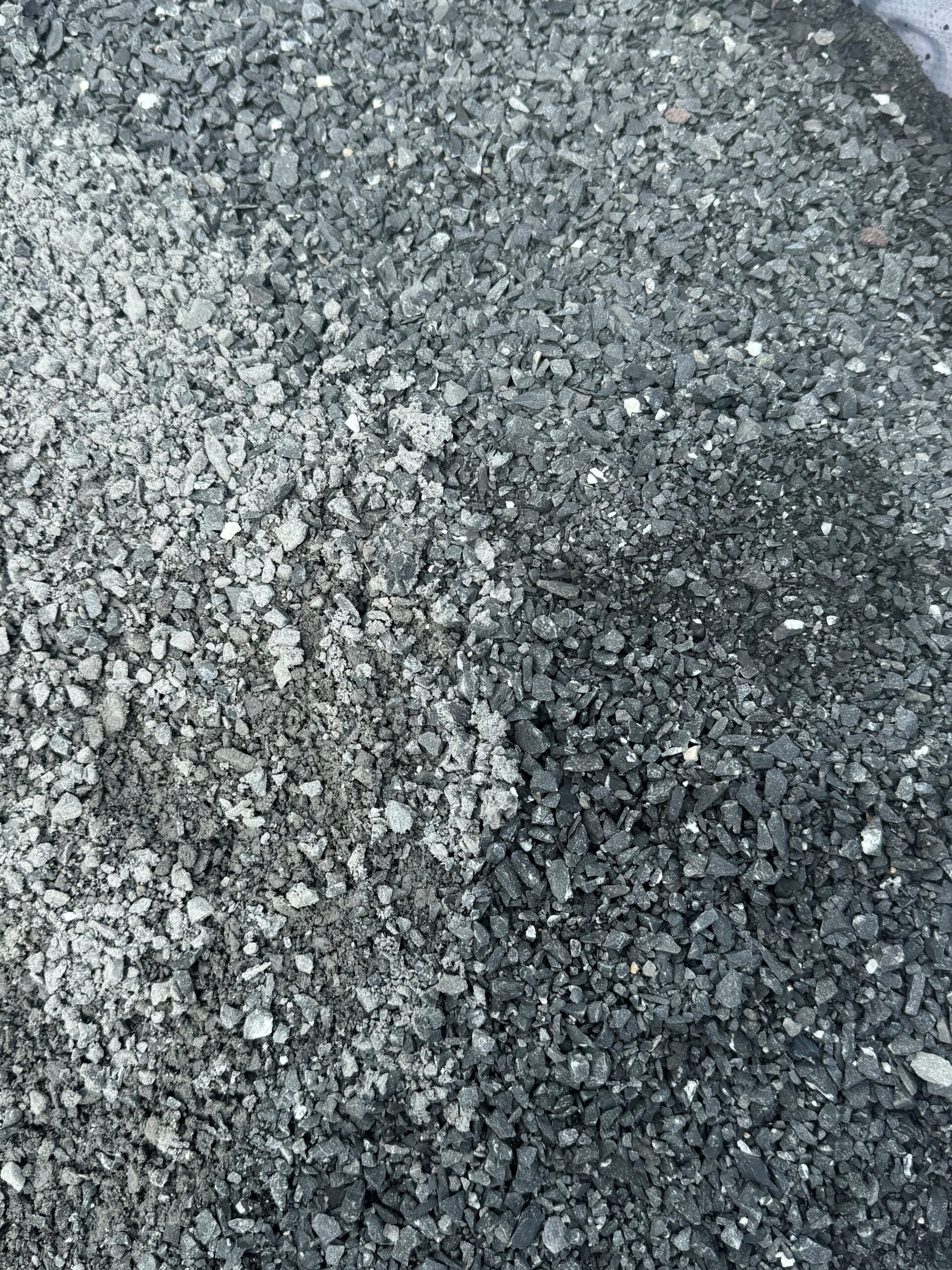 The image shows a close-up view of a mixture of different types of gravel or crushed stone. The left side of the image features lighter-colored gravel, while the right side displays darker-colored gravel.